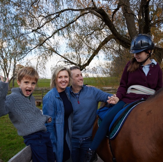 Magnolia sitting on a horse with her family—her parents, Jenny and AJ, and her brother, Grayden.