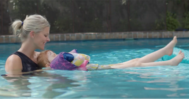 Caroline holding Minna in the water. Minna is on her back, floating.